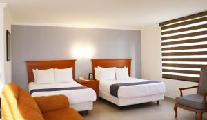 una habitación de hotel con 2 camas y una silla en Araiza Palmira Hotel y Centro de Convenciones, en La Paz