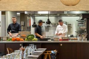 3 hommes dans une cuisine préparant de la nourriture dans une cuisine dans l'établissement Best Western Plus Hôtel Isidore, à Saint-Jacques-de-la-Lande