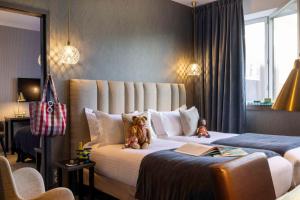 due orsacchiotti seduti su un letto in una camera d'albergo di Best Western Plus Hôtel Isidore a Saint-Jacques-de-la-Lande
