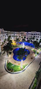 COSTA BEACH Lux Family Apartment with Pools في بوزنيقة: مسبح كبير فيه نخل امام مبنى