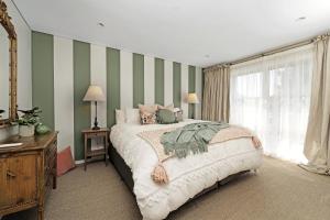 um quarto com uma cama e riscas verdes e brancas em The Hidden Door Bowral Villa -the Love of Old Bowral em Bowral