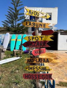 a sign with many signs on a pole with surfboards at Surf house apartment in Oualidia