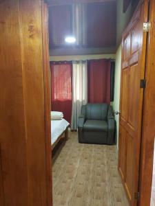 Zimmer mit einem Stuhl, einem Bett und Vorhängen in der Unterkunft Cabaña Las Colinas in Bijagua