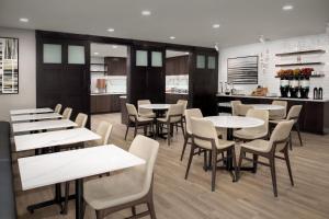 a restaurant with tables and chairs and a kitchen at Residence Inn by Marriott Dallas Grand Prairie in Grand Prairie