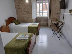 a bedroom with two beds and a tv in it at A Taberna de Gundián in Vedra