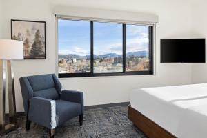 a bedroom with a bed and a chair and a large window at Element Bozeman in Bozeman