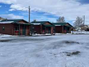 una cabaña de madera con nieve en el suelo delante en South Fork Lodge & RV Park Colorado, en South Fork