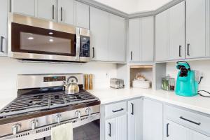 a white kitchen with a stove and a microwave at Poree Domaine Bend in Bend