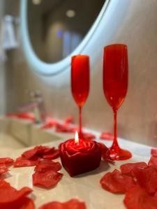 發羅拉的住宿－Bee Hotel，两杯红玻璃和一张桌子上的蜡烛