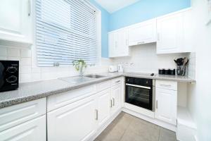 eine weiße Küche mit weißen Schränken und einem Waschbecken in der Unterkunft Brewer Street Central Apartments in London