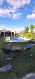 two chairs and a picnic table and a pool at Departamentos Merceditas in San Rafael