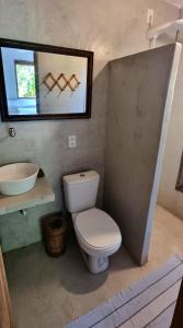 Un baño con inodoro, lavabo y espejo. en Gameleira Caraíva, en Caraíva