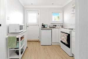 una cucina bianca con forno a microonde e piano cottura di The Hidden Door Bowral Cottage - The Love of Bowral a Bowral