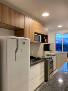 eine Küche mit einem weißen Kühlschrank und einer Mikrowelle in der Unterkunft Cariri Vivenda - Apto completo com 02 quartos climatizados, estacionamento e portaria 24 horas in Juazeiro do Norte