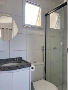 a bathroom with a toilet and a sink and a mirror at Cariri Vivenda - Apto completo com 02 quartos climatizados, estacionamento e portaria 24 horas in Juazeiro do Norte