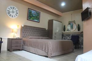 a bedroom with a large bed and a clock on the wall at Arenal Memories. in Fortuna