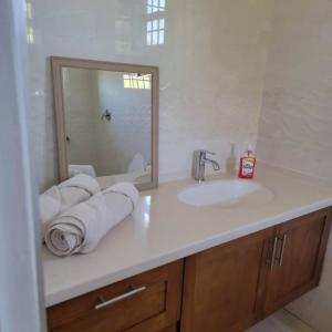 uma casa de banho com lavatório, espelho e toalhas em The Luxe Room & Suite em Saint Michael