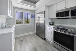 uma cozinha com armários brancos e electrodomésticos de aço inoxidável em Loggerhead 314 condo em Sanibel