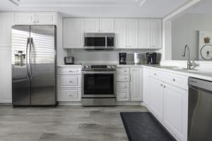 a kitchen with white cabinets and a stainless steel refrigerator at Loggerhead 314 condo in Sanibel