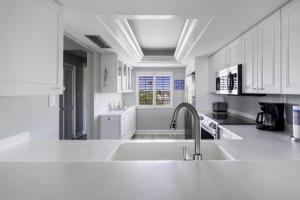 uma cozinha branca com um lavatório e um balcão em Loggerhead 314 condo em Sanibel