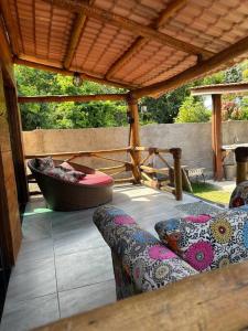 a covered patio with a couch and a tub at Chalé de Madeira, a 60m do mar em condomínio in Vera Cruz de Itaparica