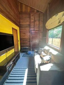 a living room with a couch and a flat screen tv at Chalé de Madeira, a 60m do mar em condomínio in Vera Cruz de Itaparica +2 photos