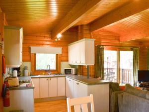 a kitchen with white cabinets and a wooden ceiling at Red Kite Lodge in Legbourne