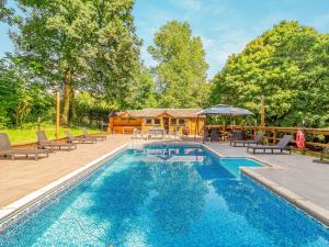 a pool with chairs and an umbrella next to a house at Dai Boy Cabin - Uk46403 in Cowbridge