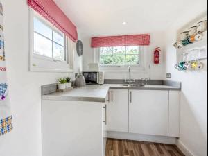 a kitchen with white cabinets and a sink at Gwyneths Haven - Uk46404 in Cowbridge