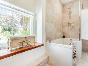 a bathroom with a tub and a window at Llwynhelig House - Uk46395 in Cowbridge