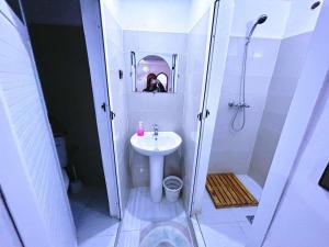 a white bathroom with a sink and a shower at Riad pizzeria Marhaba in Akhendachou nʼAït Ouffi