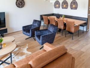 ein Wohnzimmer mit einem Sofa, Tischen und Stühlen in der Unterkunft 20-person group home in the heart of Friesland in Leons