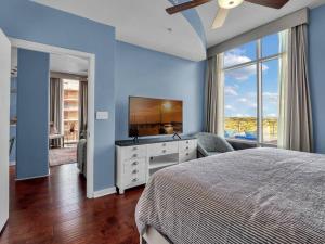 Dormitorio azul con cama y TV en 2/2 PENTHOUSE DOWNTOWN with large Billiard room, en Orlando