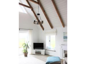 uma sala de estar com paredes brancas e um tecto com vigas de madeira em Tranquil holiday home with garden em Kronsgaard
