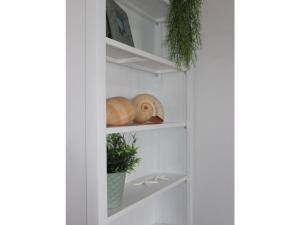 uma estante de livros branca com duas conchas e uma planta em Tranquil holiday home with garden em Kronsgaard