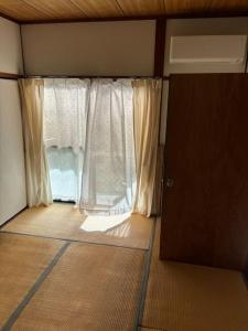 Cette petite chambre dispose d'une fenêtre et d'une porte. dans l'établissement 高知県　みどりの家, à Gomen