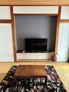 高知県　みどりの家 في Gomen: غرفة معيشة مع طاولة قهوة وتلفزيون بشاشة مسطحة