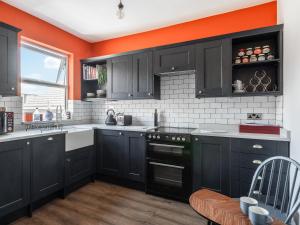 una cocina con armarios negros y una pared de color naranja en Hereward House en Margate