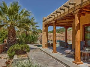 a patio with a wooden deck and a palm tree at Beautiful holiday home with private pool in Cala Vadella