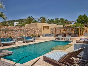 a swimming pool with chaises and chairs next to a house at Beautiful holiday home with private pool in Cala Vadella