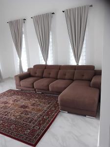 Sofá marrón en la sala de estar con alfombra en Homestay Rumi en Macang