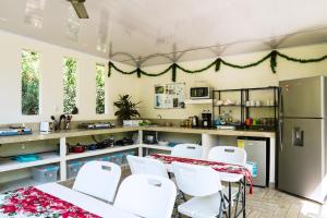 a kitchen with white chairs and a table and a refrigerator at House in the palm forest in Carrillo
