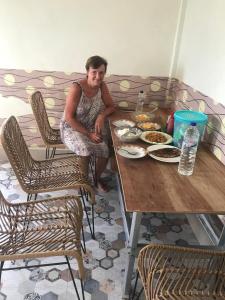 Eine Frau, die an einem Tisch mit einem Teller Essen sitzt. in der Unterkunft ORA KOMODO HOME STAY in Komodo