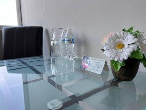 a glass table with a vase of flowers and a bottle of water at Depa doble centrico con Restaurante Terraza in Orizaba