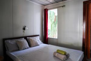 a bedroom with a bed with two pillows and a window at House in the palm forest in Carrillo