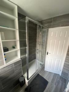 baño con ducha y puerta blanca en Chic City Retreat Immaculate 2-Bed Oasis in London, en Londres
