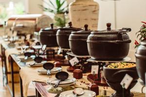 a row of pots and pans on a table with food at Recanto Da Paz Hotel Fazenda in Atibaia