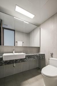 W łazience znajduje się umywalka, toaleta i lustro. w obiekcie Ocean Terrace Yeosu w mieście Yeosu