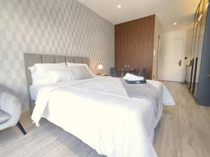 een slaapkamer met een groot wit bed en een stoel bij BeKAWS: Suite in Quito