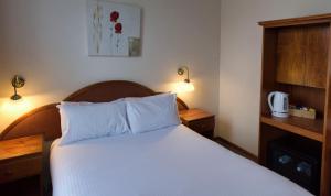 una camera da letto con un letto con lenzuola bianche e due lampade di The Metropole Guest House Katoomba a Katoomba